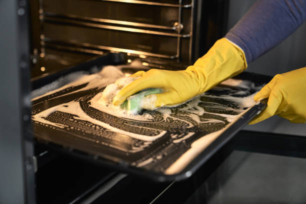 Close up of woman worker cleaning oven at home