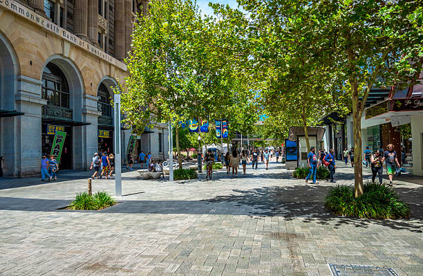 A scenic urban walkway adorned with lush green trees, where people enjoy the vibrant atmosphere of the city, strolling and interacting. Perfect blend of nature and urban life