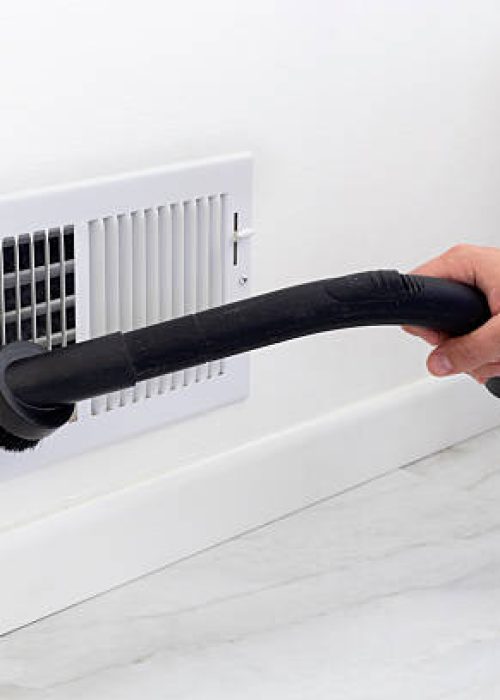 A cleaner using a vacuum to clean the air vent cover