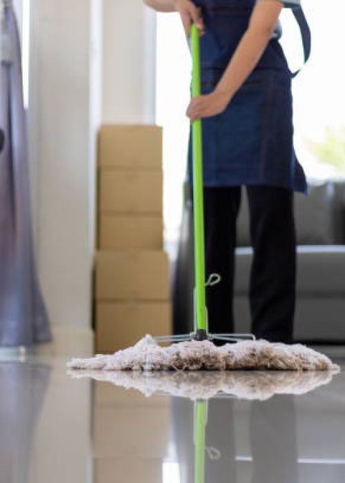 Cleaner is mopping floors at home with a mop.