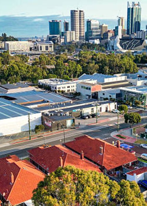 Cinematic drone view of Perth city showcasing the skyline, architecture, and surrounding landscape on a clear day.