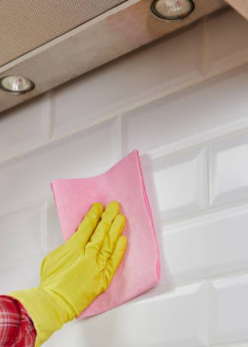 Employee hand in rubber protective glove with micro fiber cloth washing ceramic tiles in the kitchen