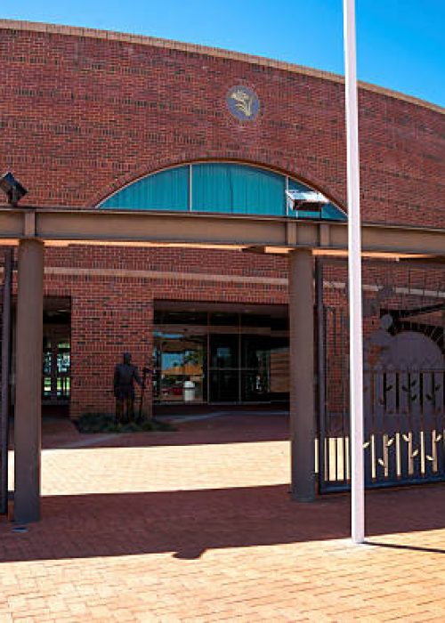 A contemporary civic building featuring a distinct brick facade, showcasing a stylish metal gate and pathway