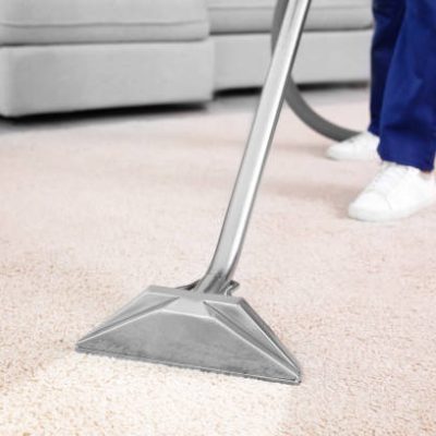 Worker removing dirt from carpet indoors, closeup. Cleaning service