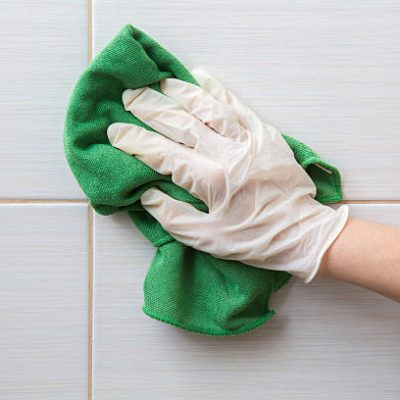 Hand in protective glove cleaning tiles with rag. Early spring cleaning or regular clean up.