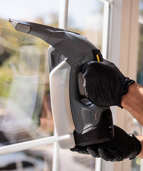Home cleaning professional using a mechanical tool to deep-clean windows in urban apartment